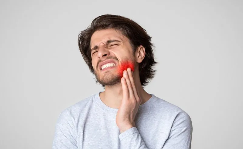 Man experiencing severe tooth pain requiring emergency dental care